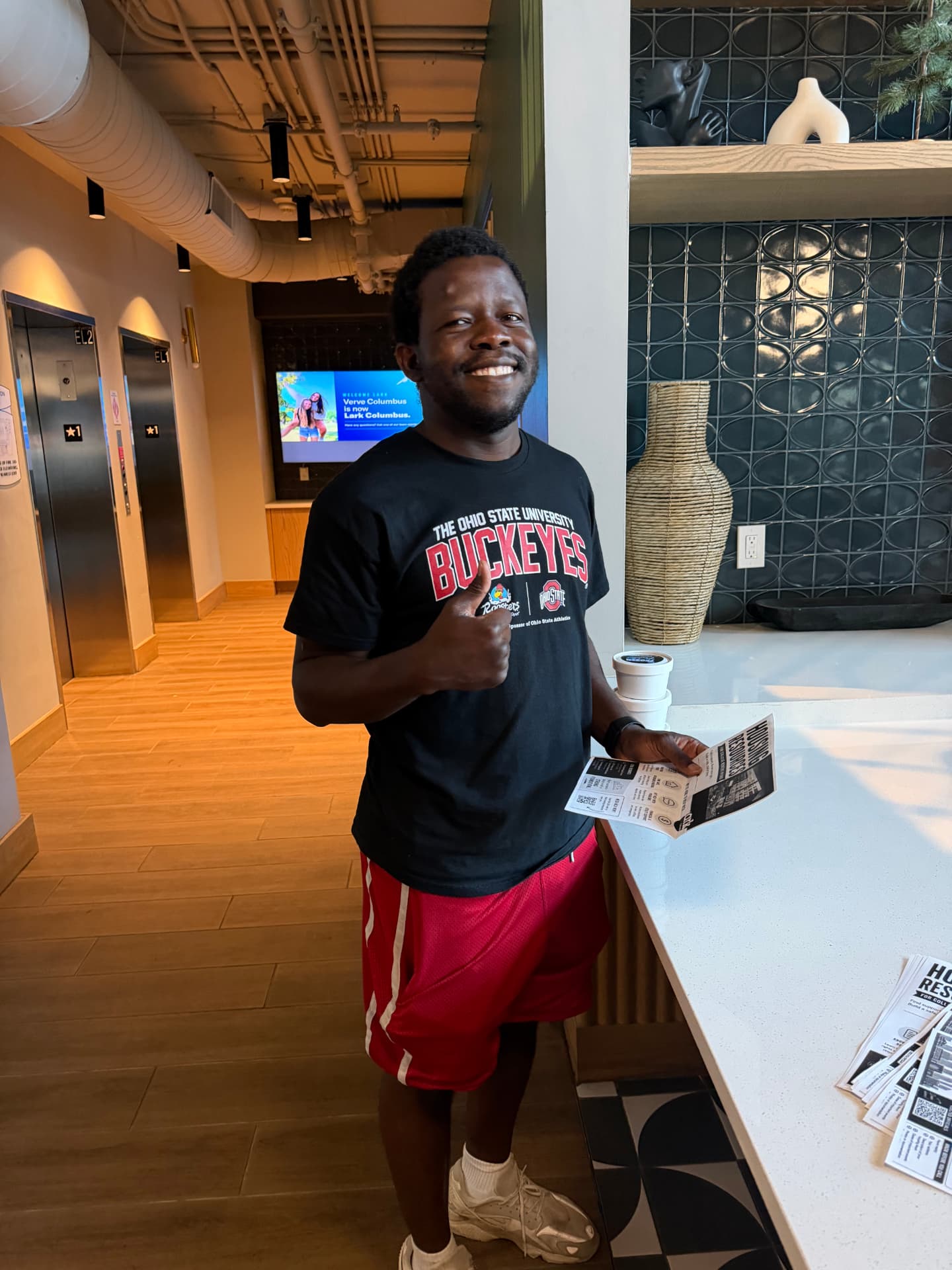 Student giving a thumbs up while reading a Keep Knocking housing resources flyer