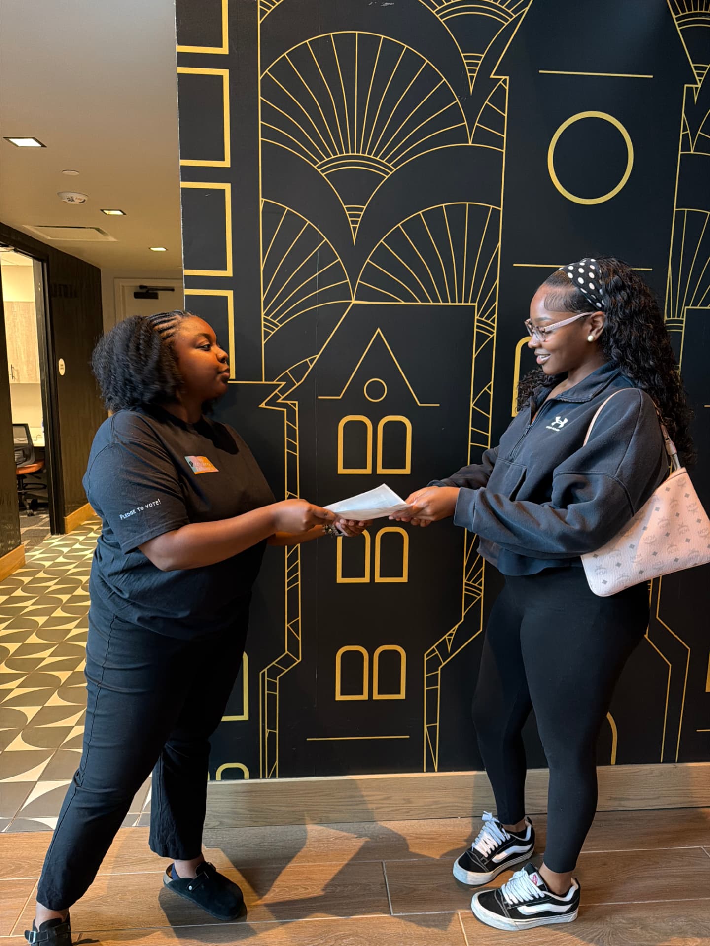 Fellow handing housing rights literature to a student in an apartment lobby
